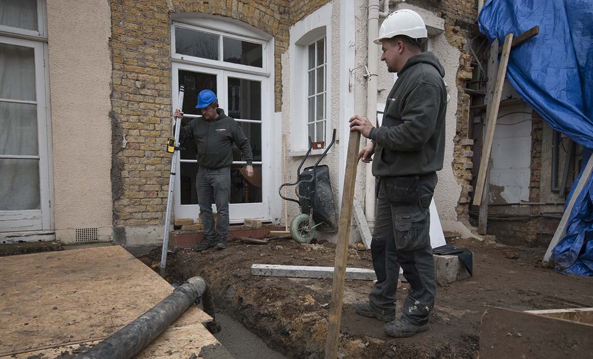 two builders pouring concrete, two men at work, two builders at the backyard